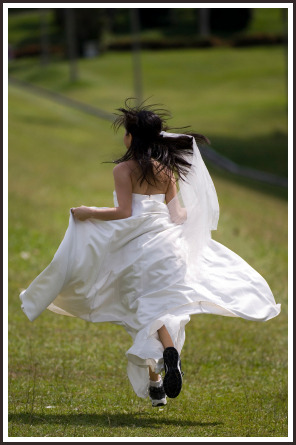 A woman in her wedding dress runs away in training shoes